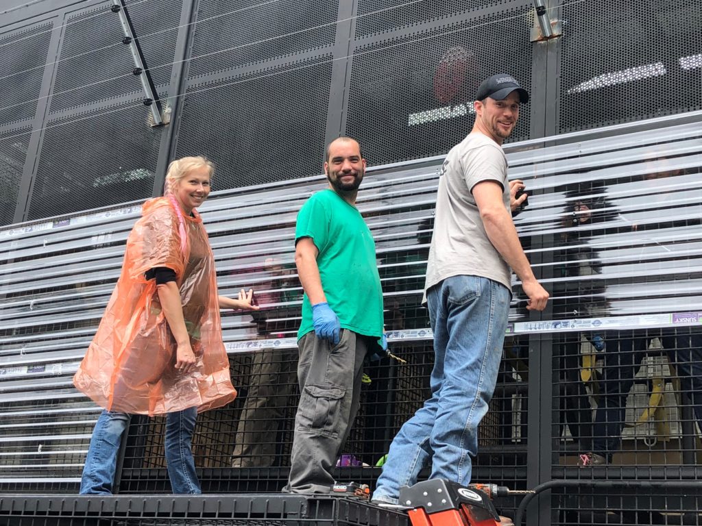 
﻿Project Chimps’ chimpanzee care and facilities team members, Brooke, Ryan and Lucas, install plastic sheeting outside the open-air mesh of the chimps’ large group villas.