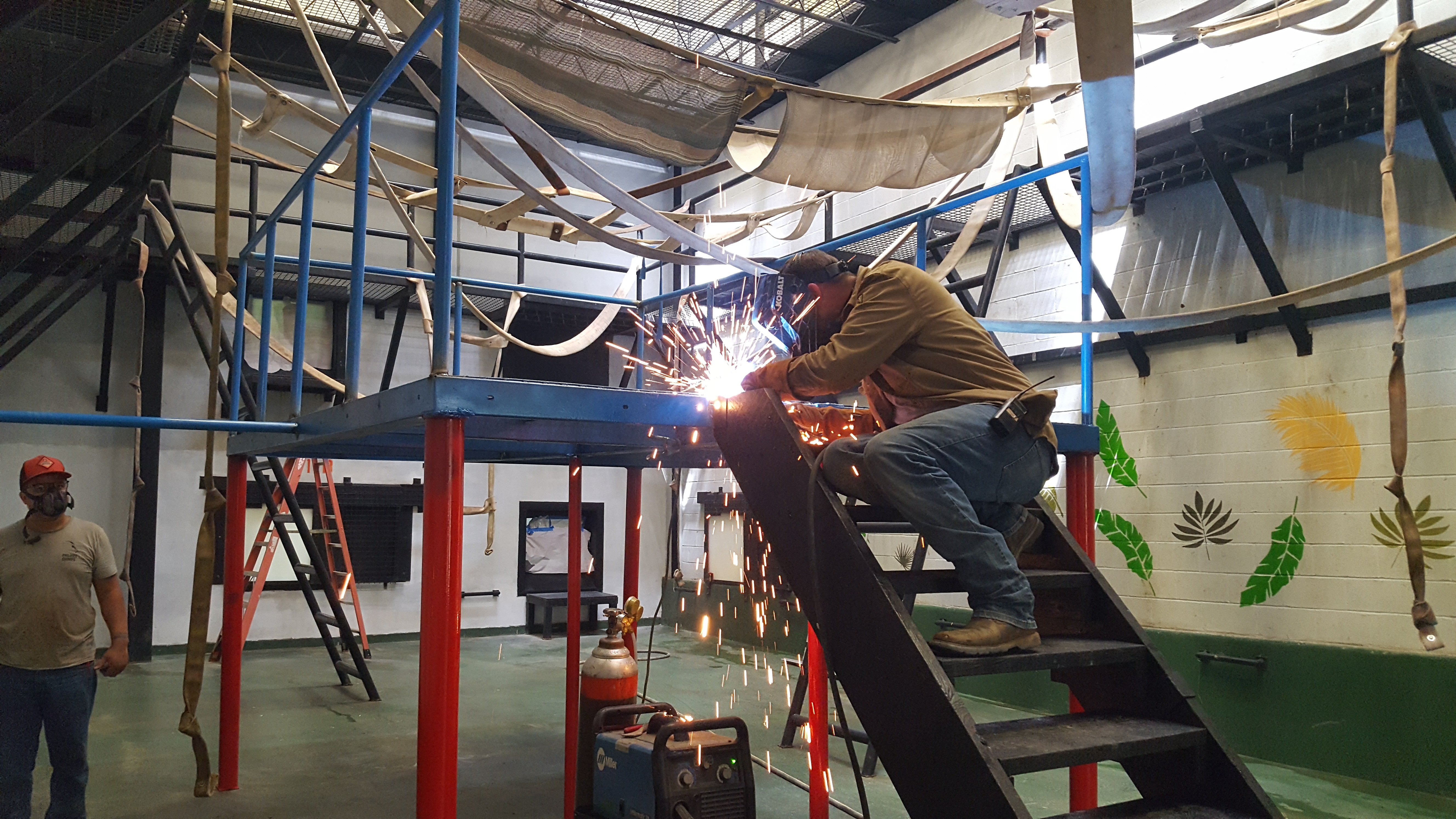 two employees welding a metal climbing structure